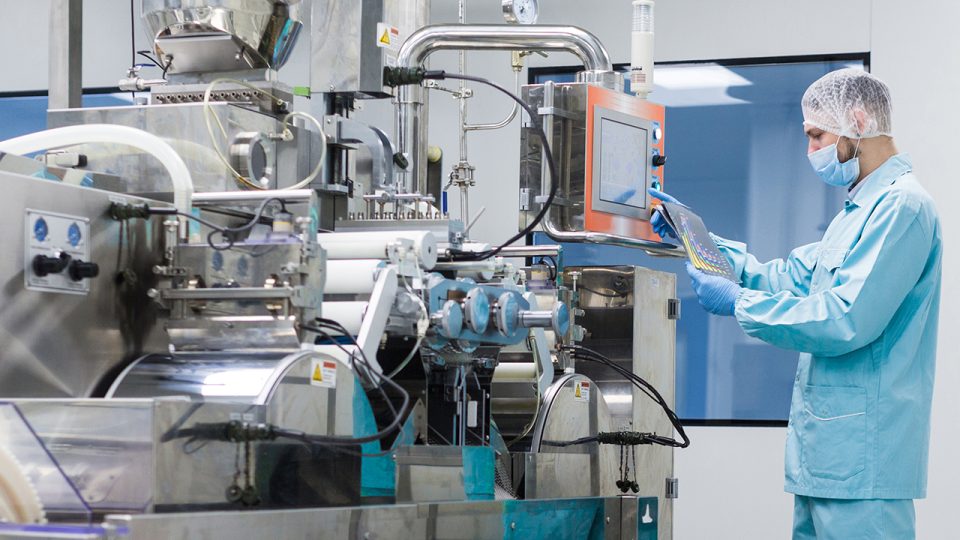 widescreen picture, caucasian scientist in blue lab suit trying to fix manufacture machine with shafts in clean factory